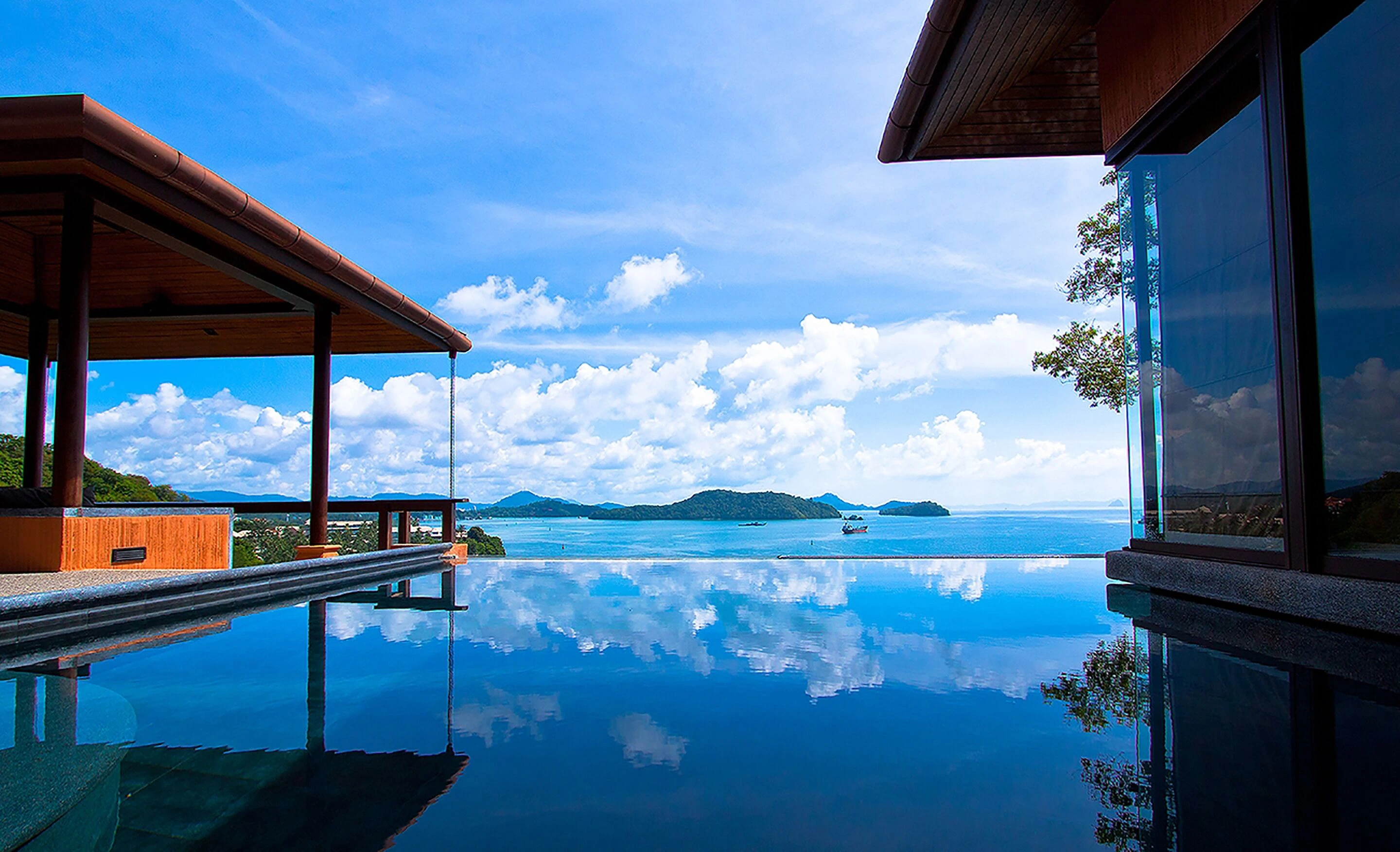 Sri panwa infinity pool villa  overlooking turquoise ocean under bright sunny sky, creating a serene tropical paradise atmosphere.